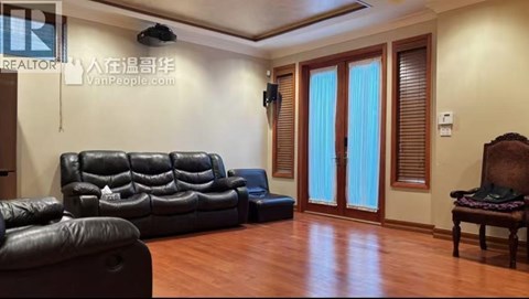 A living room with a black leather couch and a wooden chair.