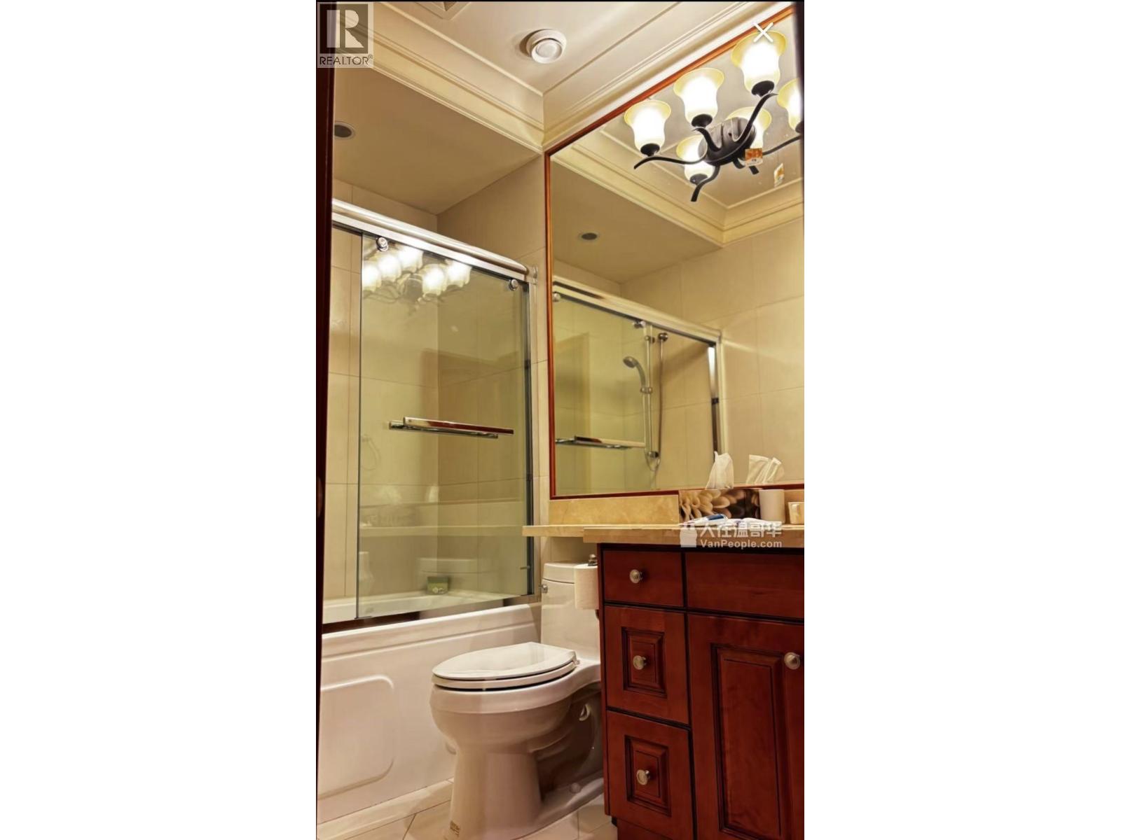 A bathroom with a toilet, sink and mirror.