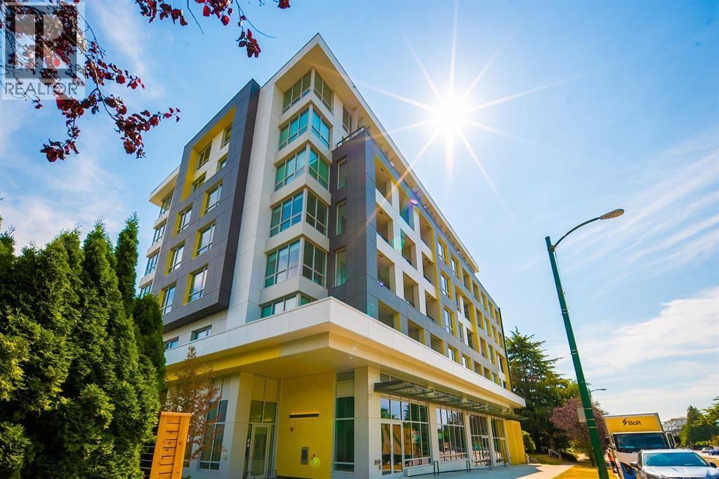 A modern building with a yellow entrance and a bright sun in the sky.