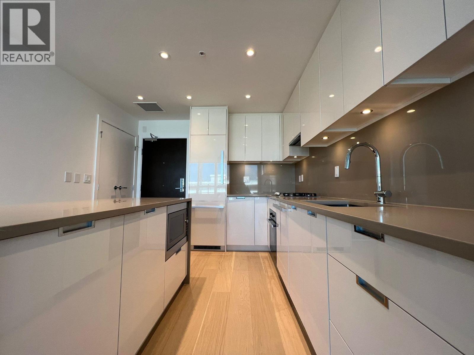 A modern kitchen with white cabinets and a wooden floor.