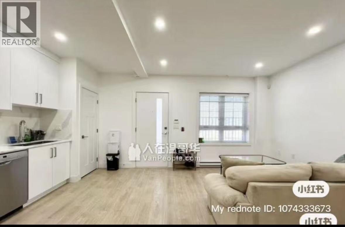 A well-lit, spacious living room with a kitchen area in the background.