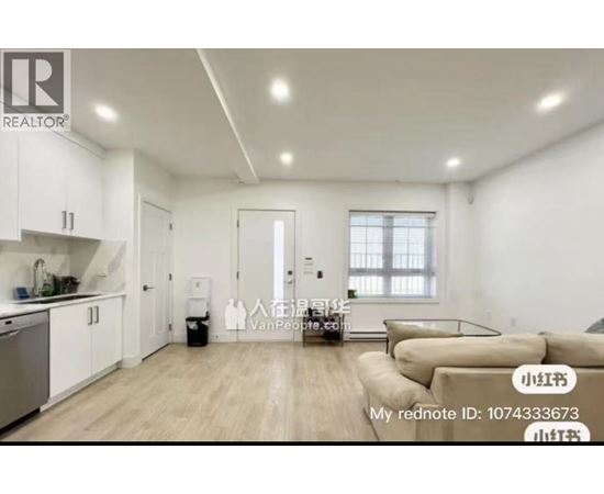 A well-lit, spacious living room with a kitchen area in the background.