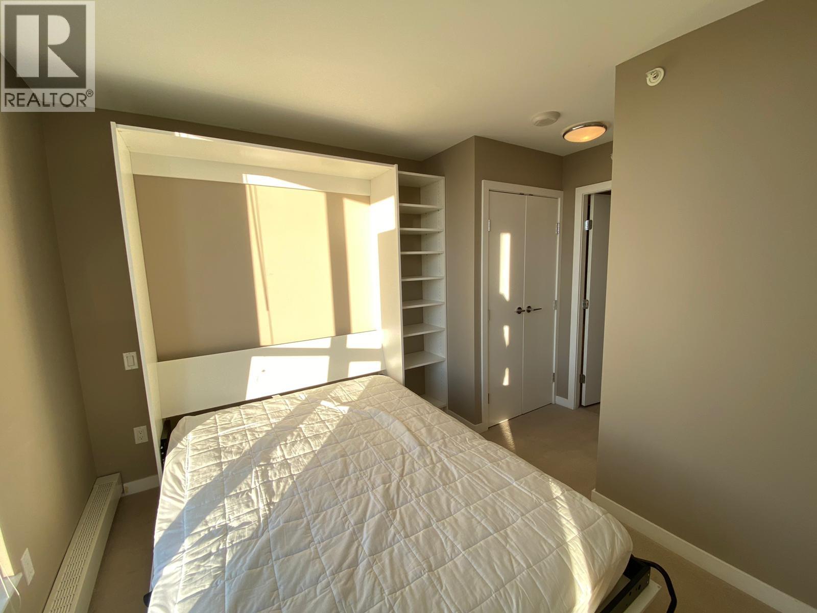 A bedroom with a bed, a closet, and a window.