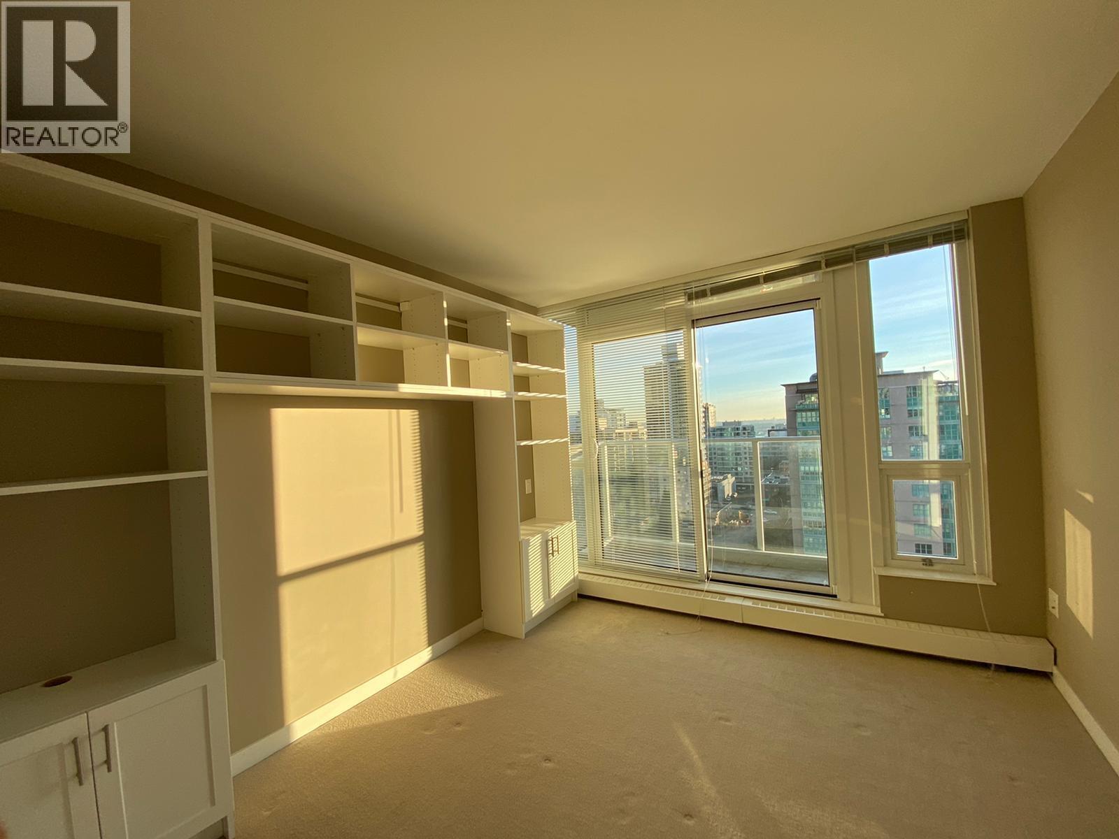 A spacious, empty room with a view of the city through the windows.