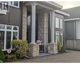 A house with a brown and white facade has a sign that says "For Sale".
