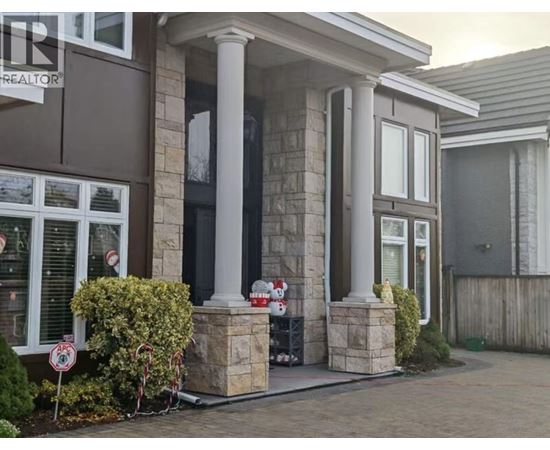 A house with a brown and white facade has a sign that says "For Sale".