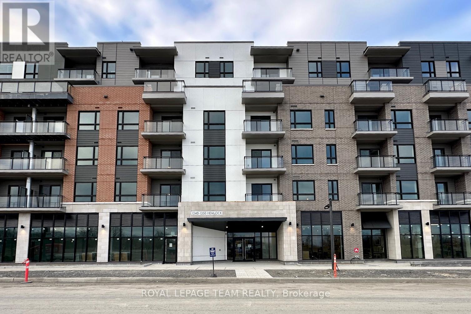 A large, modern apartment building with a white entrance and balconies on each floor.