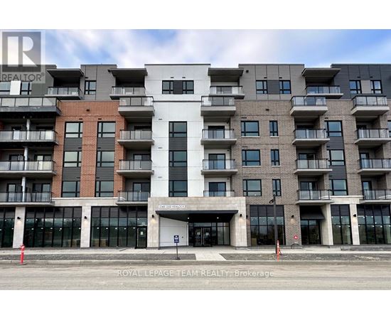 A large, modern apartment building with a white entrance and balconies on each floor.