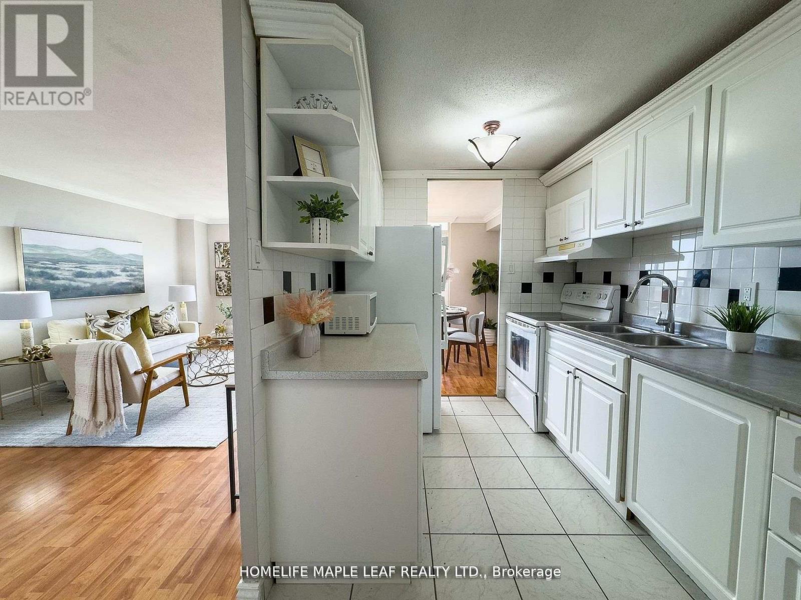 A modern kitchen with white cabinets and a wooden floor.