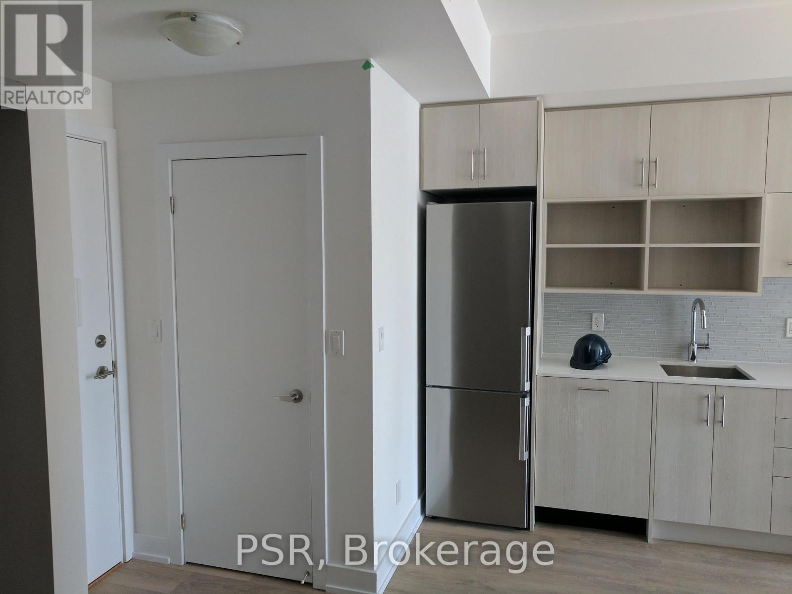 A kitchen with a refrigerator, sink, and cabinets.