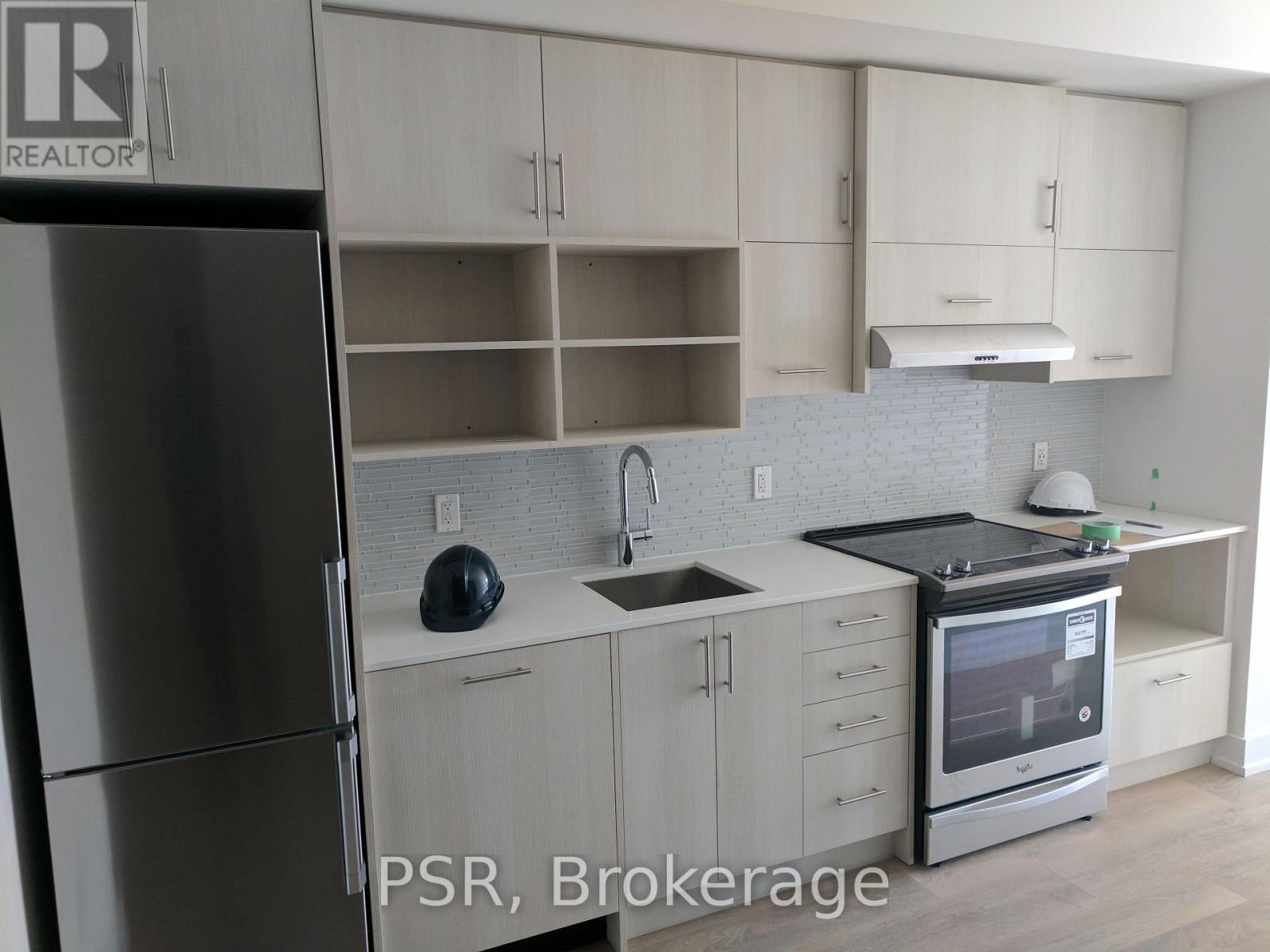 A kitchen with a refrigerator, sink, and stove.