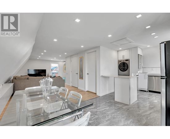 A modern kitchen with a glass dining table and a refrigerator.