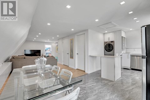 A modern kitchen with a glass dining table and a refrigerator.