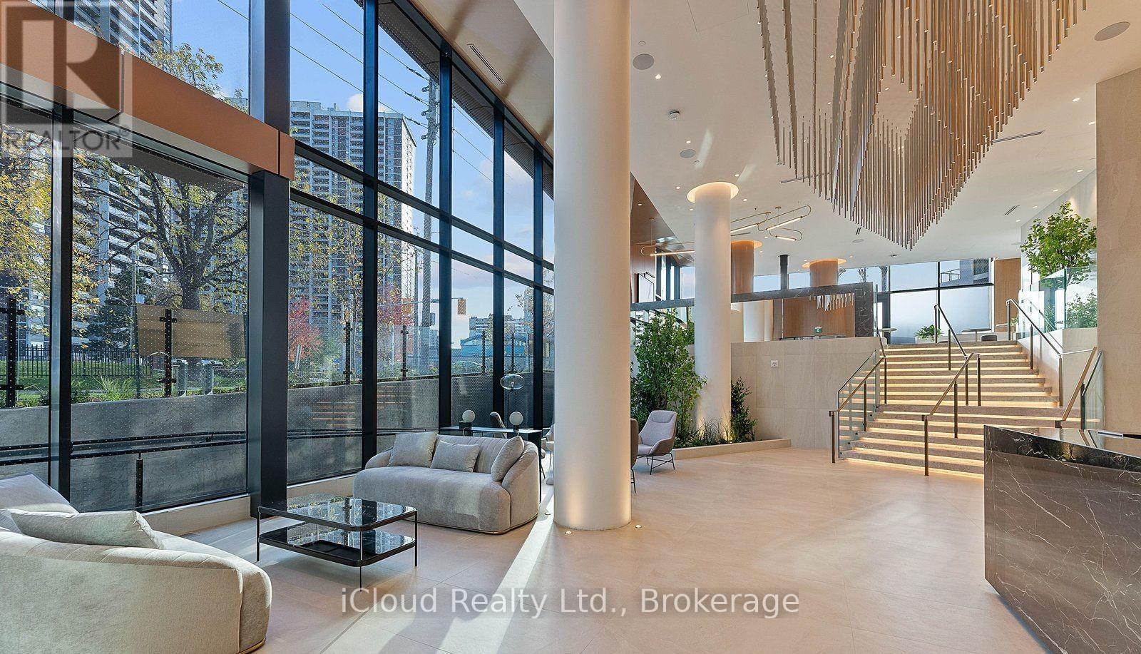 A modern interior space with a staircase, large windows, and a wooden ceiling.