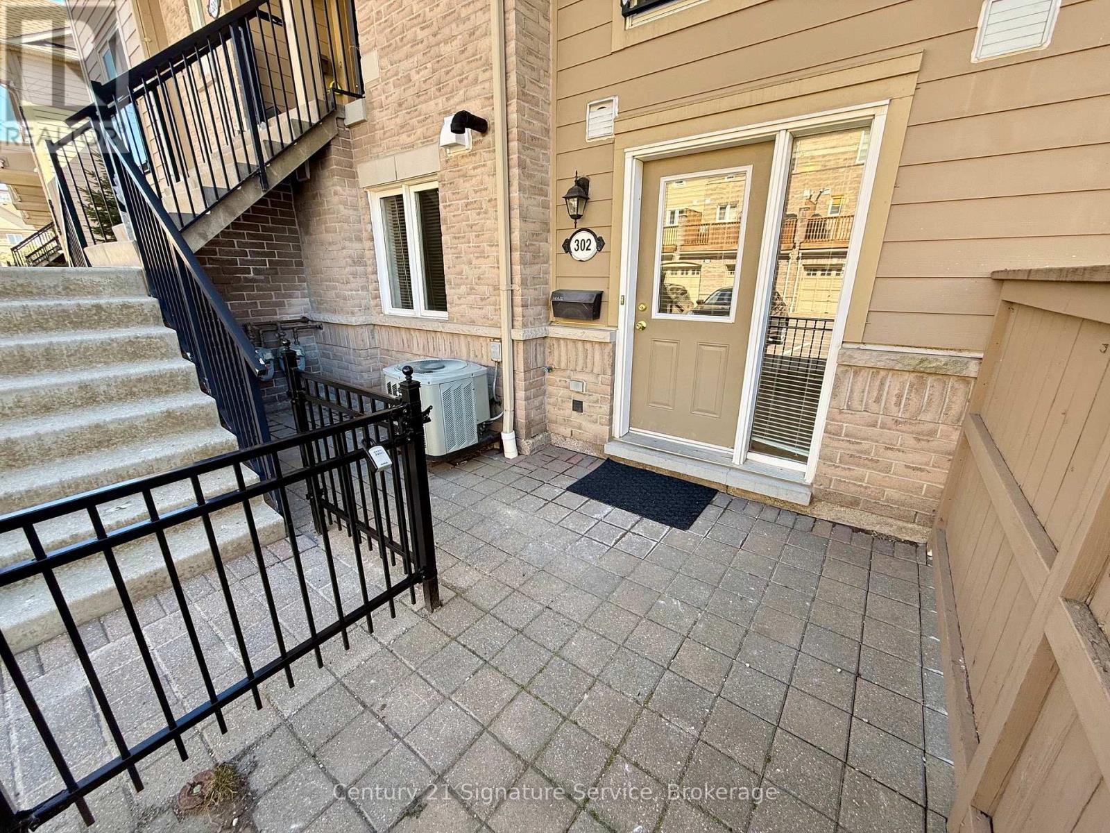 A front porch with a black railing and a white door.