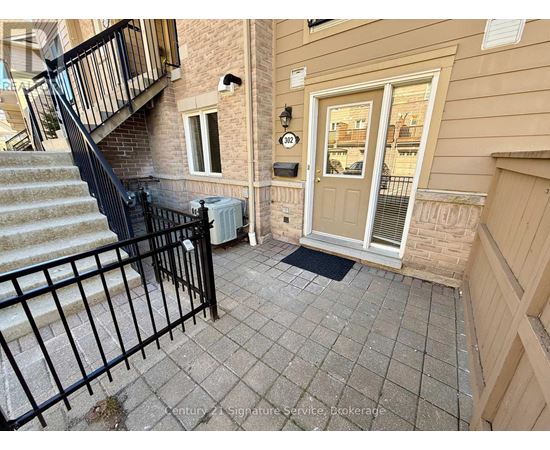 A front porch with a black railing and a white door.