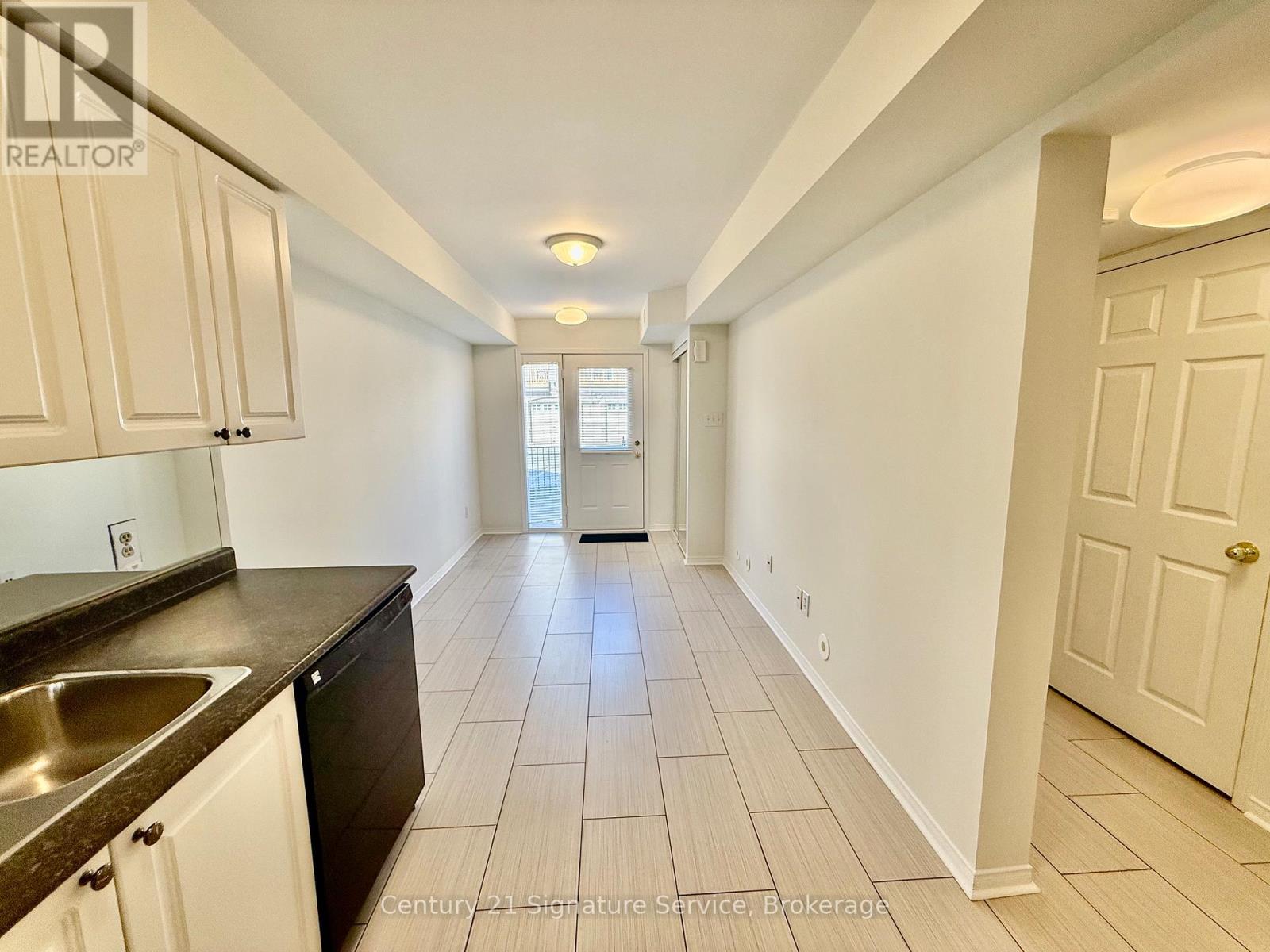 A long hallway with white walls and tile flooring.