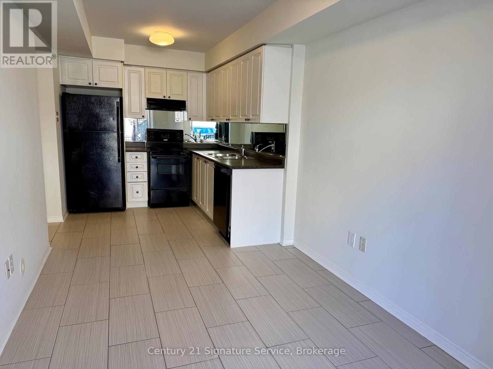 A kitchen with white cabinets and black appliances.