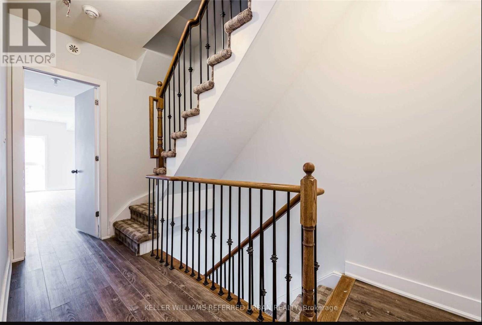 A staircase with a wooden handrail and black balusters.