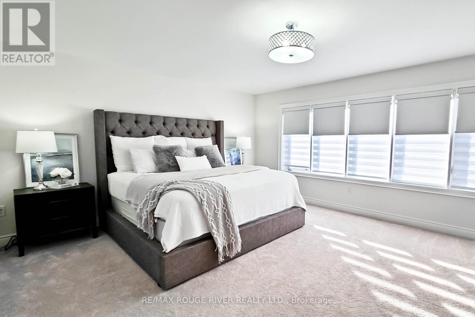 A bedroom with a large bed and a nightstand with a lamp.