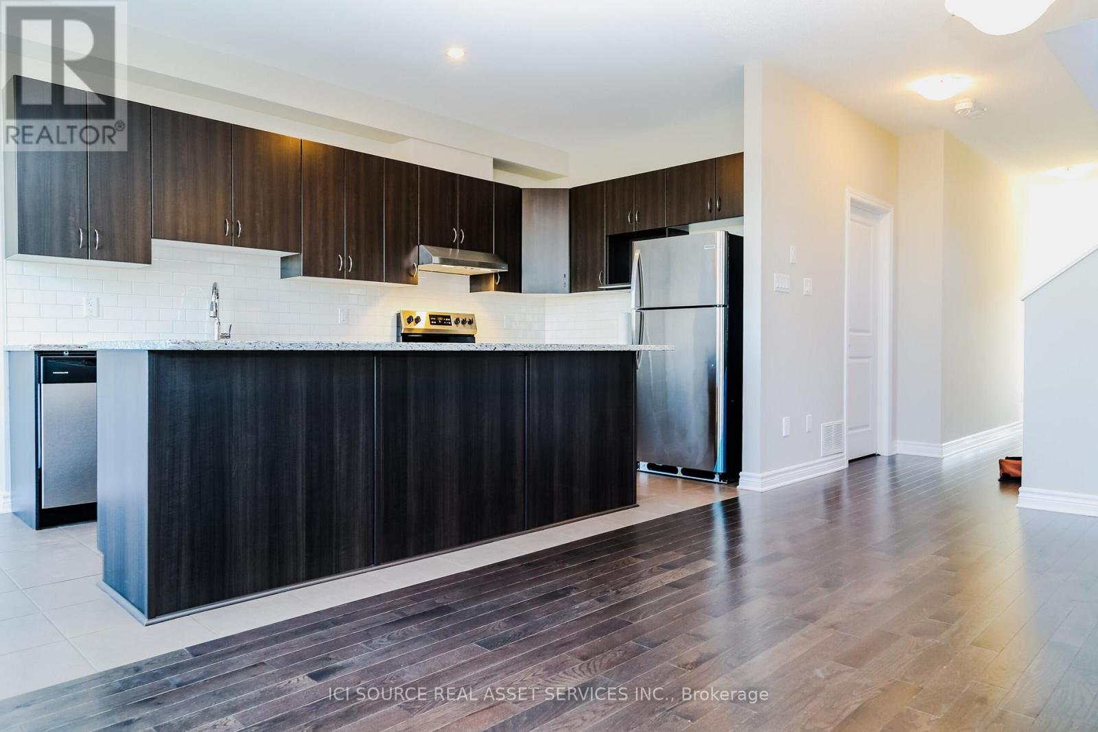 A modern kitchen with dark wood cabinets and stainless steel appliances.