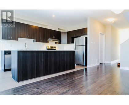 A modern kitchen with dark wood cabinets and stainless steel appliances.