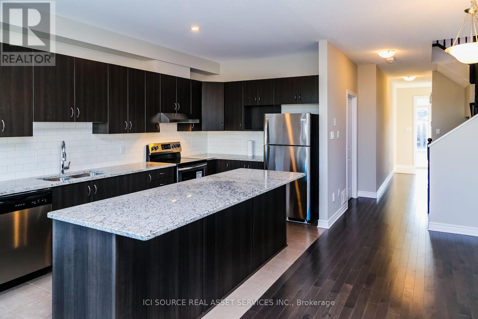 A modern kitchen with dark wood cabinets and stainless steel appliances.