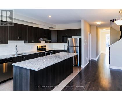 A modern kitchen with dark wood cabinets and stainless steel appliances.