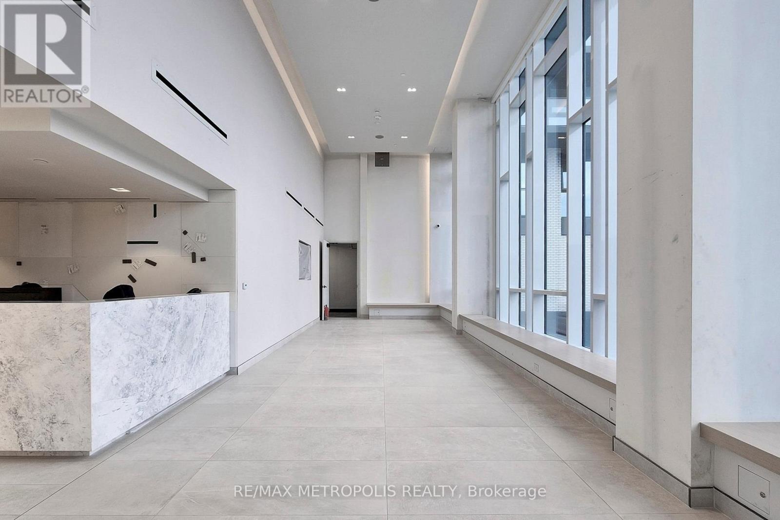 A spacious hallway with a reception desk on the left and a row of windows on the right.
