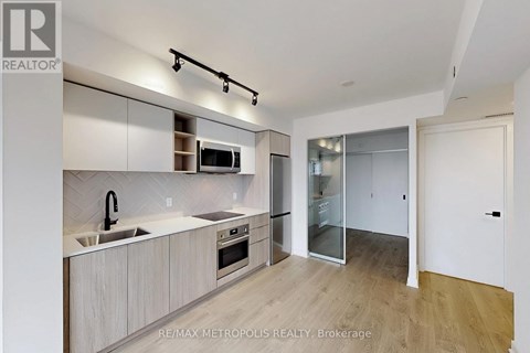 A modern kitchen with white cabinets and a wooden floor.