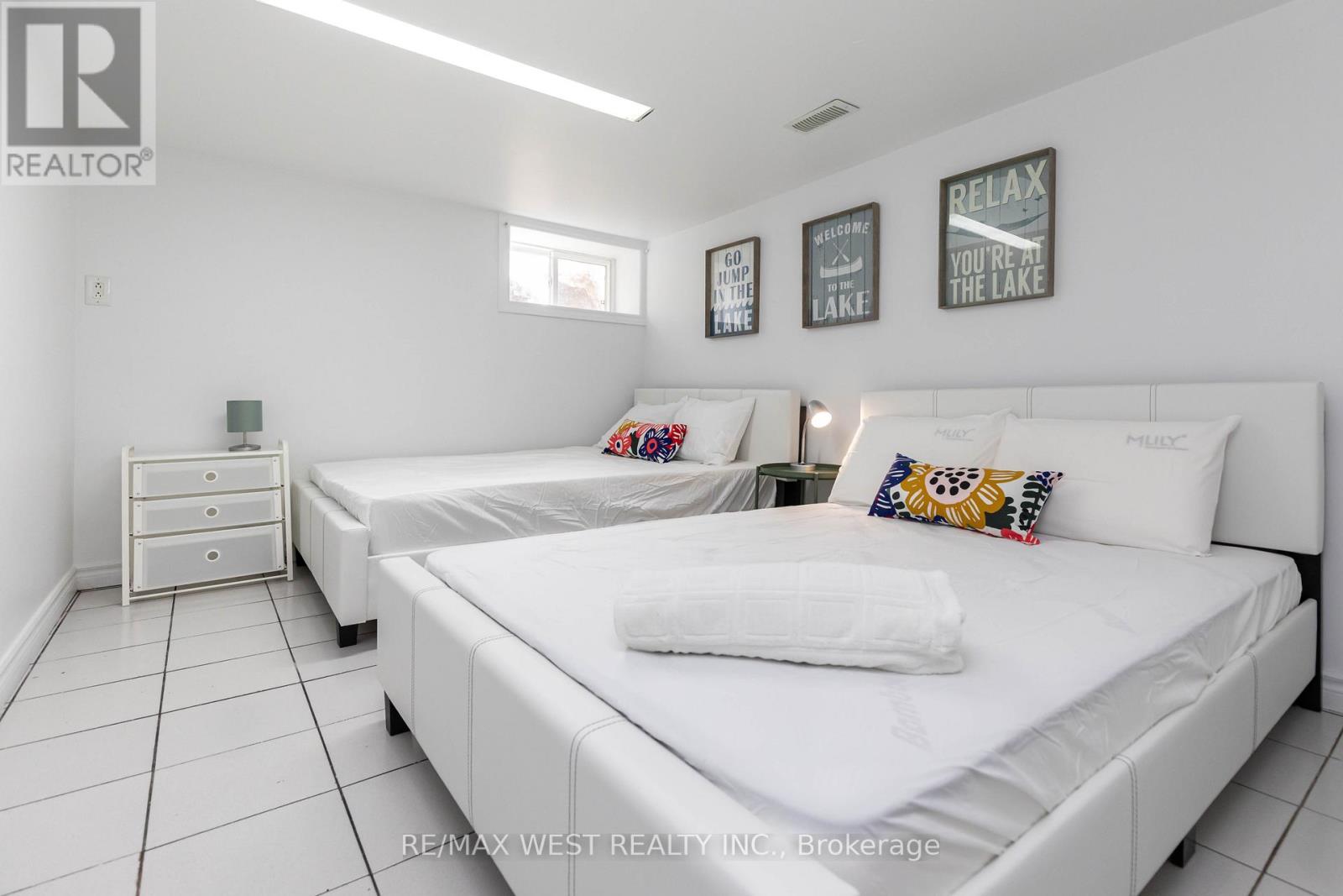 A bedroom with two beds and a nightstand.