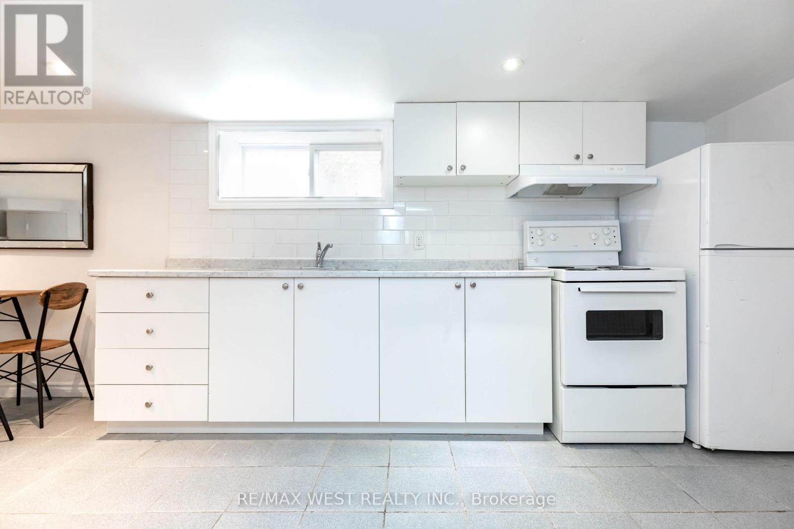 A white kitchen with a re/max west realty logo.