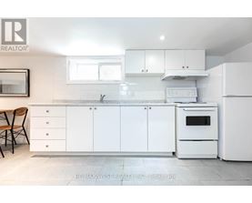 A white kitchen with a re/max west realty logo.