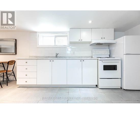 A white kitchen with a re/max west realty logo.