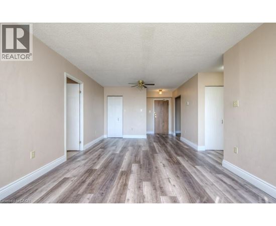A spacious room with wood flooring and a ceiling fan.