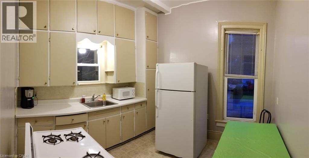 A small kitchen with a white fridge and a green table.