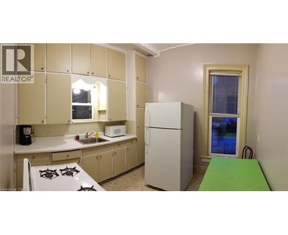 A small kitchen with a white fridge and a green table.
