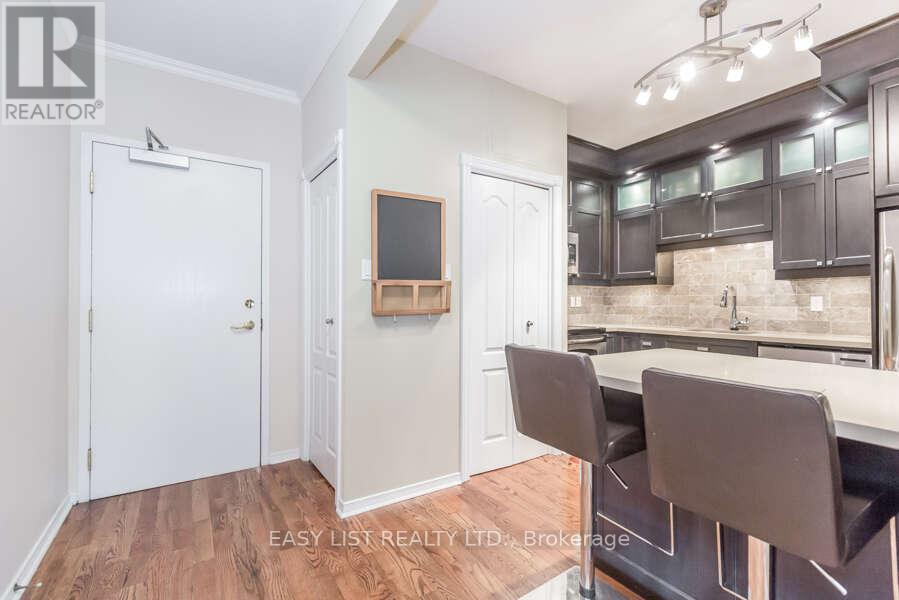 A kitchen with a white door, a white counter, and brown chairs.