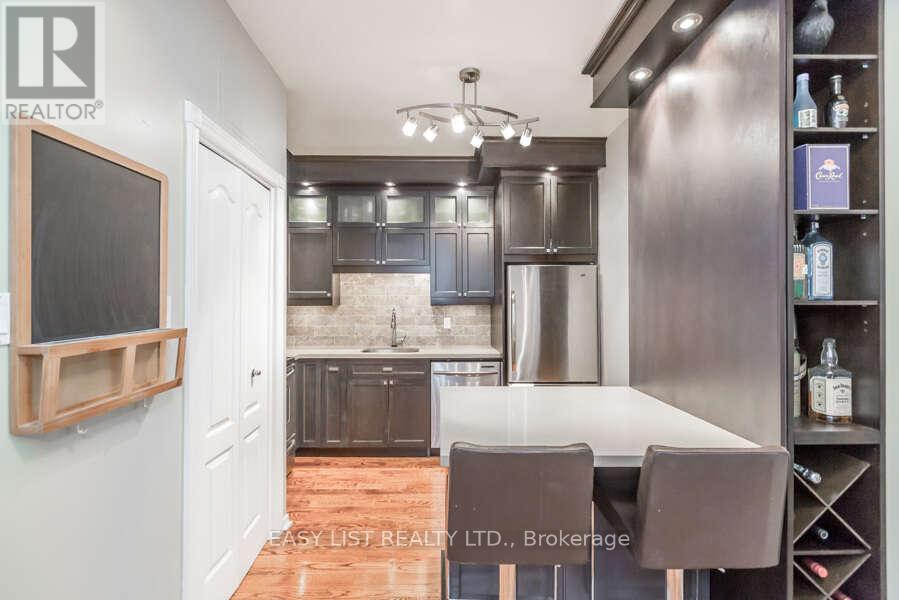 A modern kitchen with a wooden floor and stainless steel appliances.
