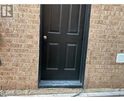 A black door with a gold handle is set in a brick wall.