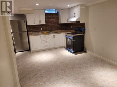 A kitchen with white cabinets and a brick backsplash is shown.