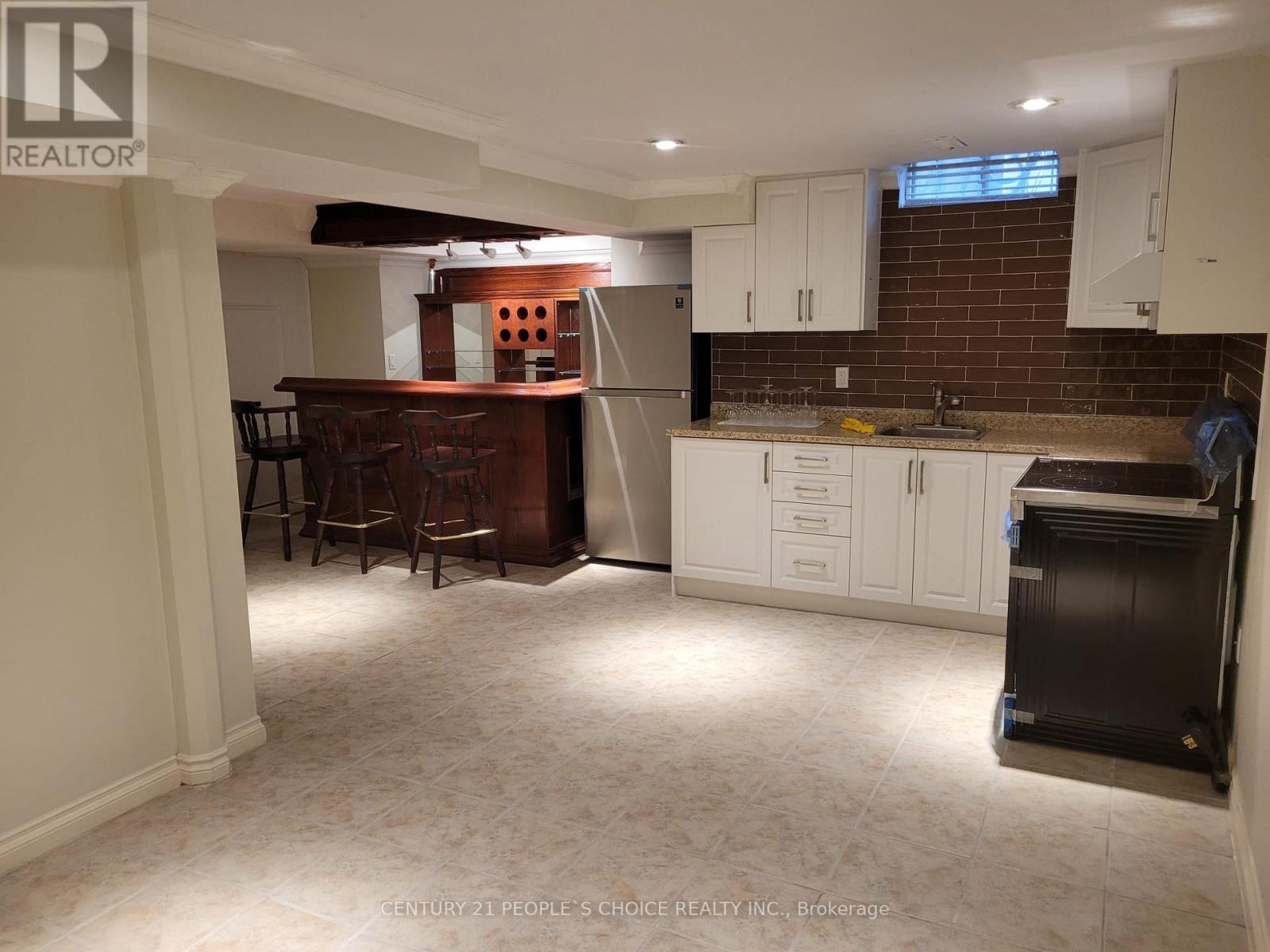 A kitchen with white cabinets and a brick wall.