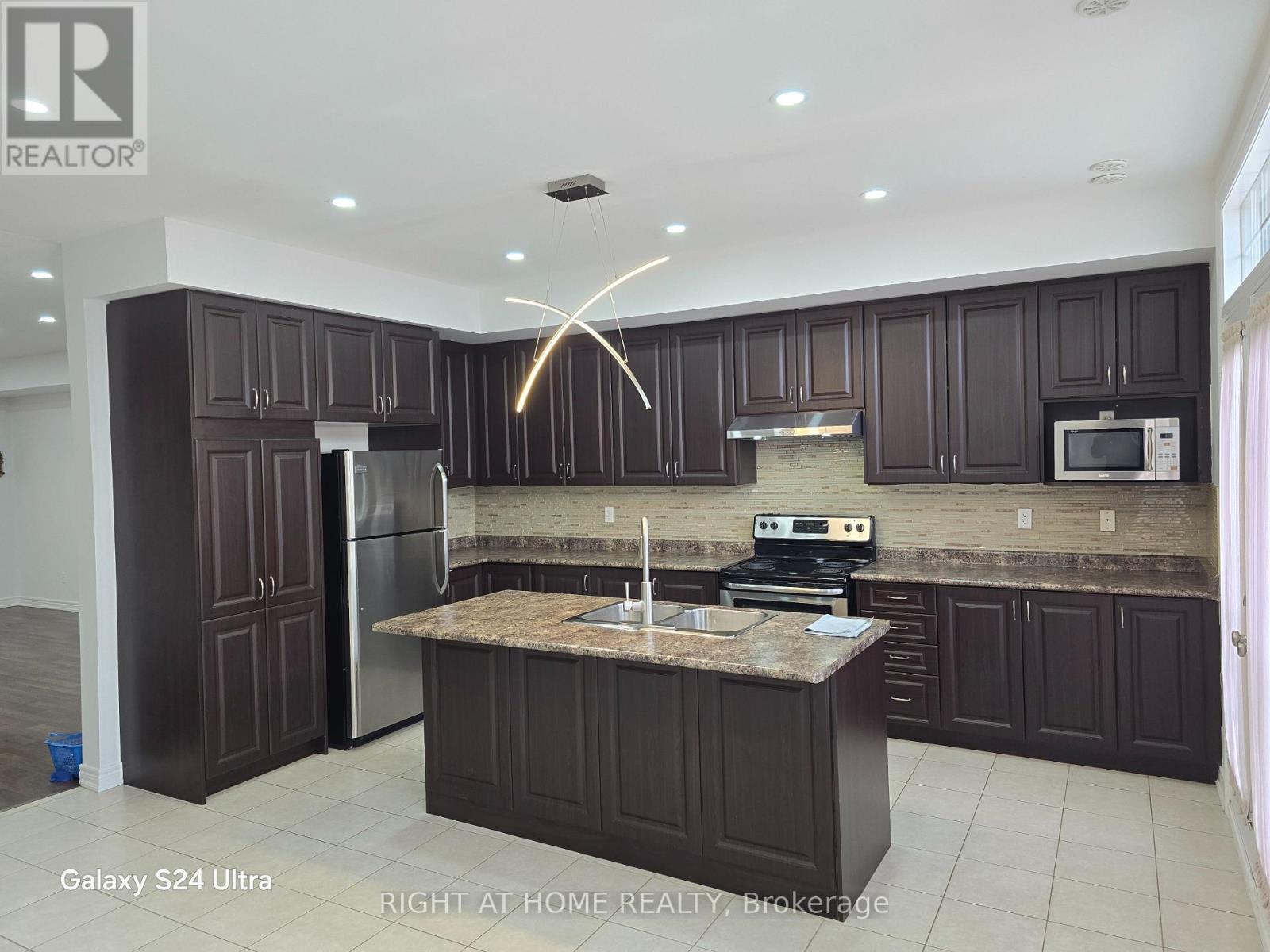A kitchen with dark brown cabinets and a granite countertop.