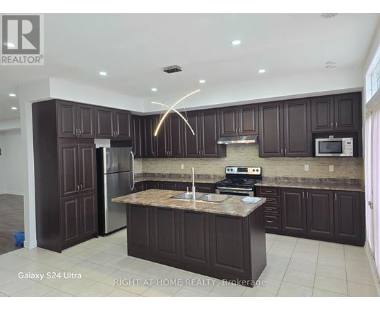 A kitchen with dark brown cabinets and a granite countertop.