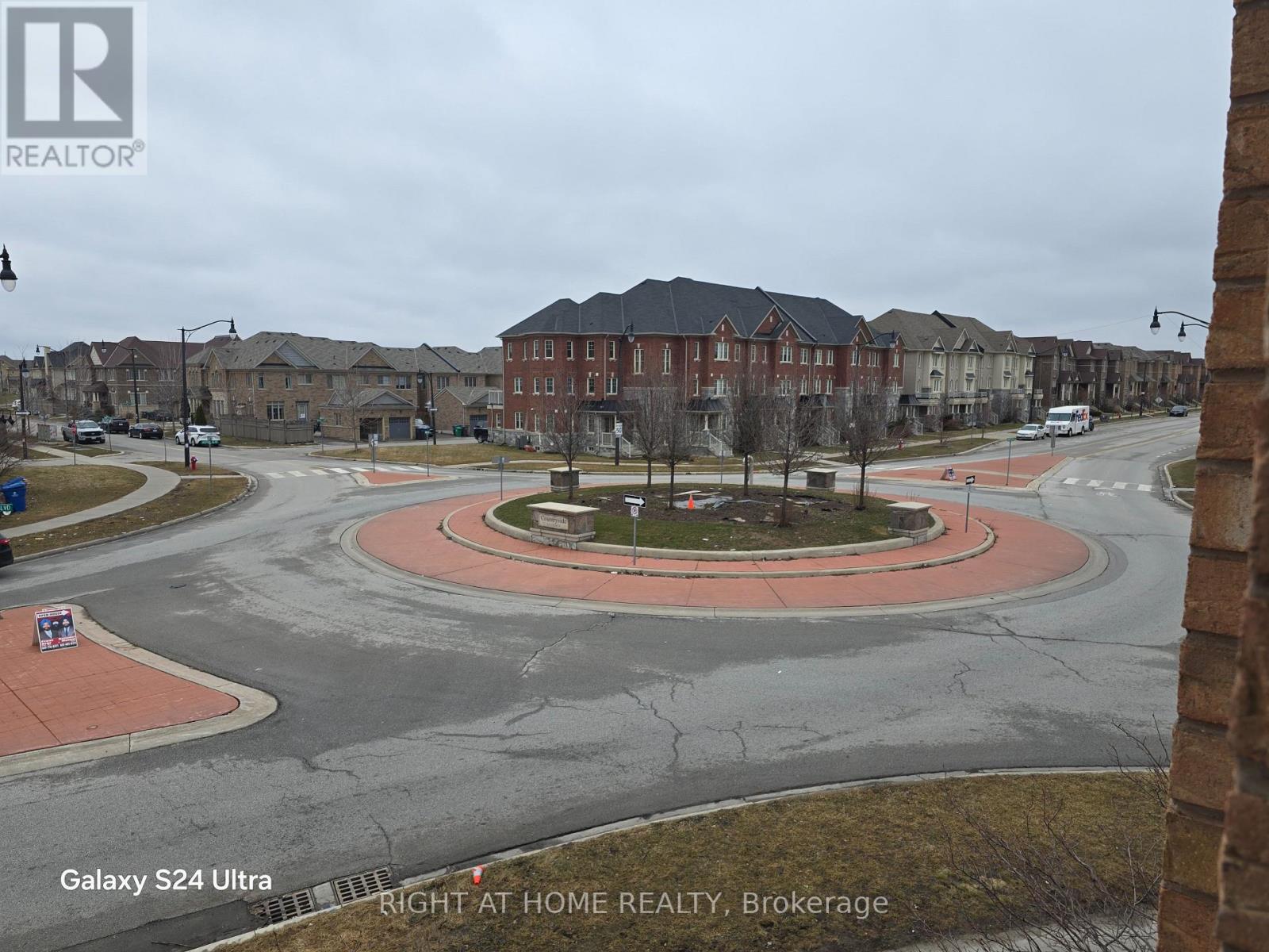 A view of a roundabout in a residential area with a sign for Right at Home Realty, Brokerage.