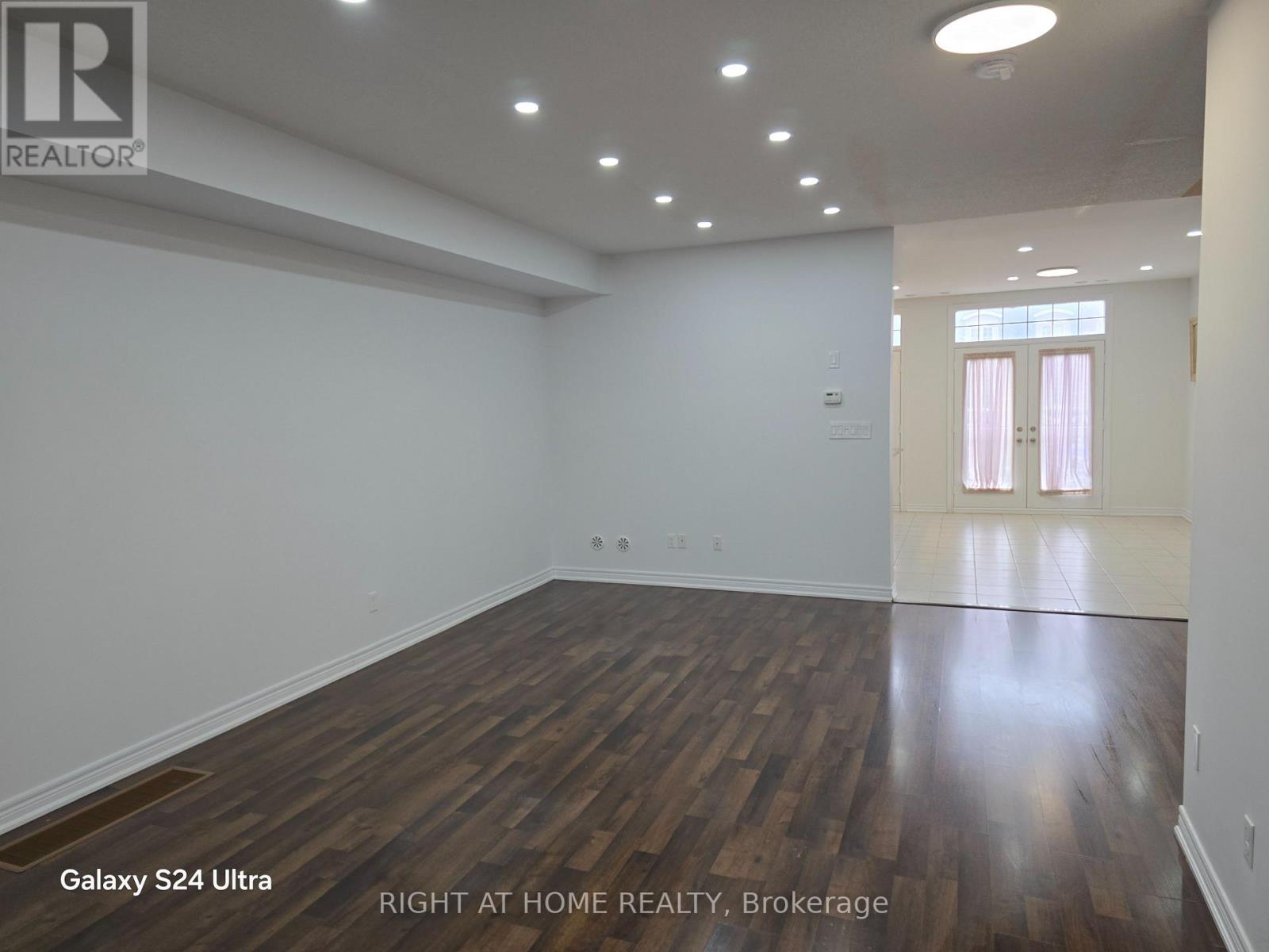 A room with wooden flooring and white walls, with a door on the right side.