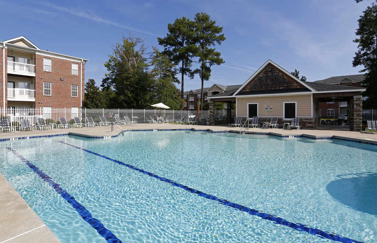 A large swimming pool with blue water and a building in the background.