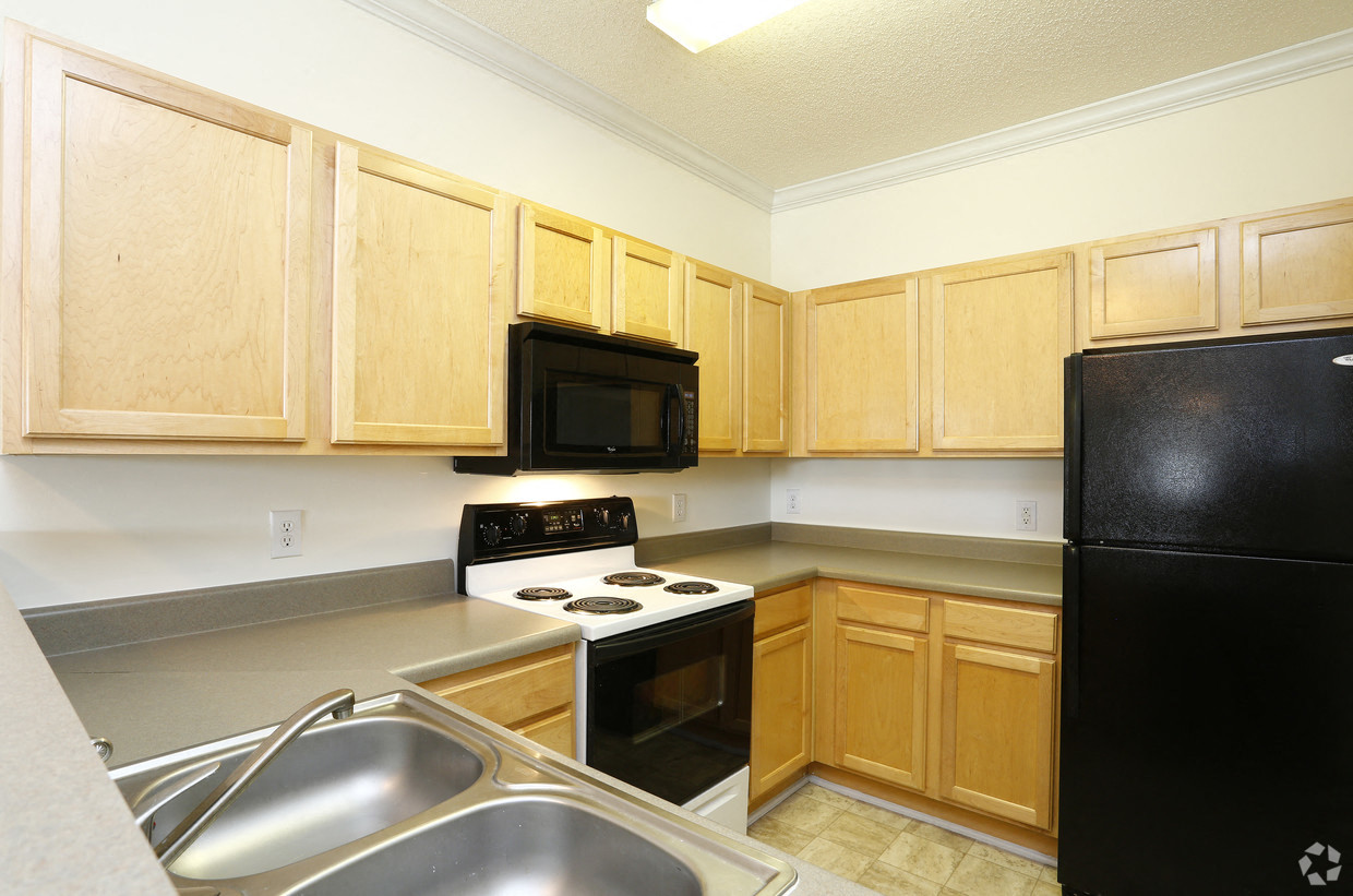 A kitchen with wooden cabinets and a black fridge.