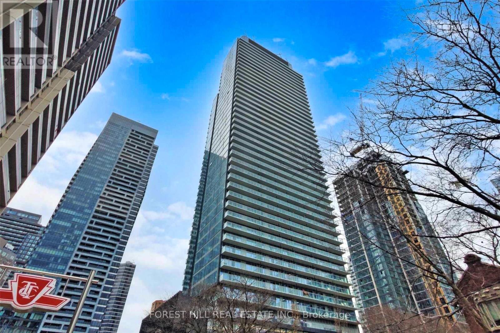 A tall building with a glass facade stands in front of other skyscrapers.