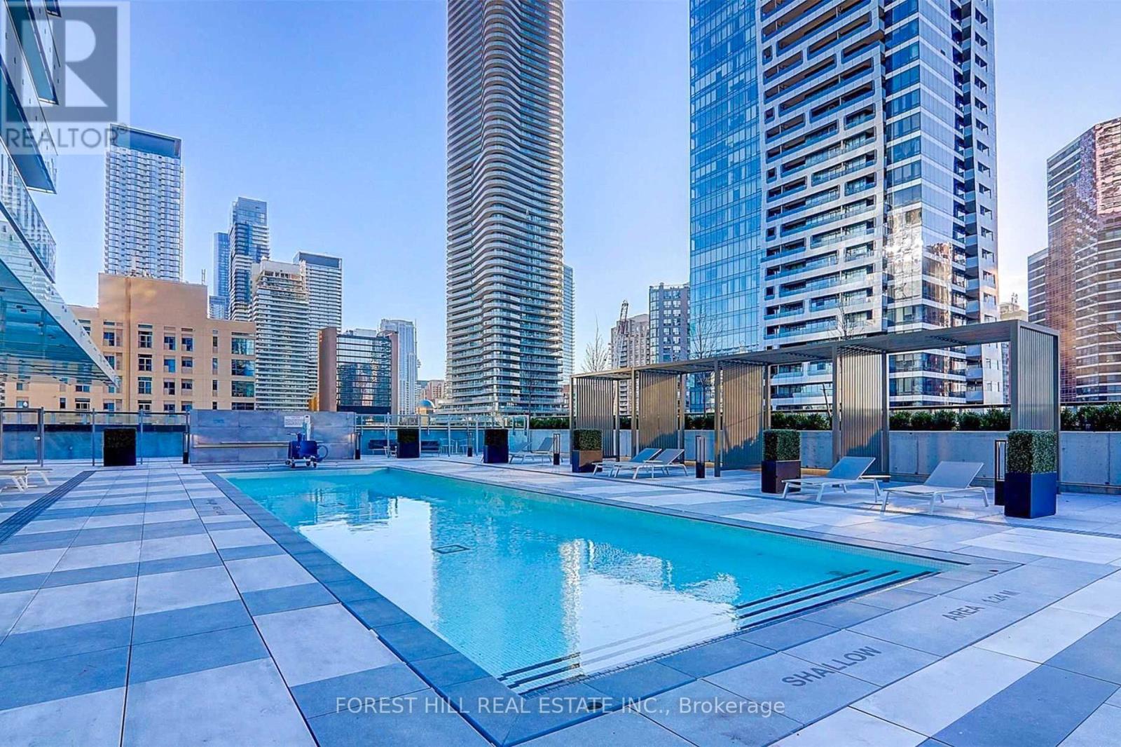 A swimming pool on a rooftop with a city skyline in the background.